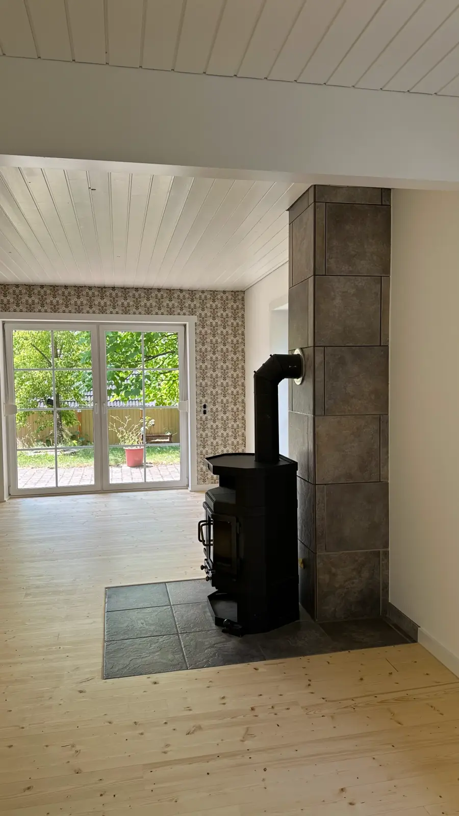 Wohnhaus K6 nach der Umsetzung: Blick in den Wohnraum mit Kaminofen und Terrassentür, vor dem Einzug.